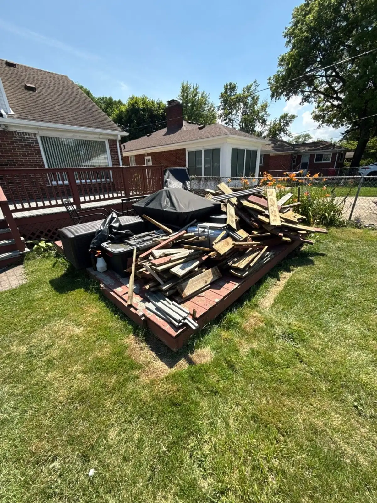 Deck boards and wood debris piled on a deck in a backyard