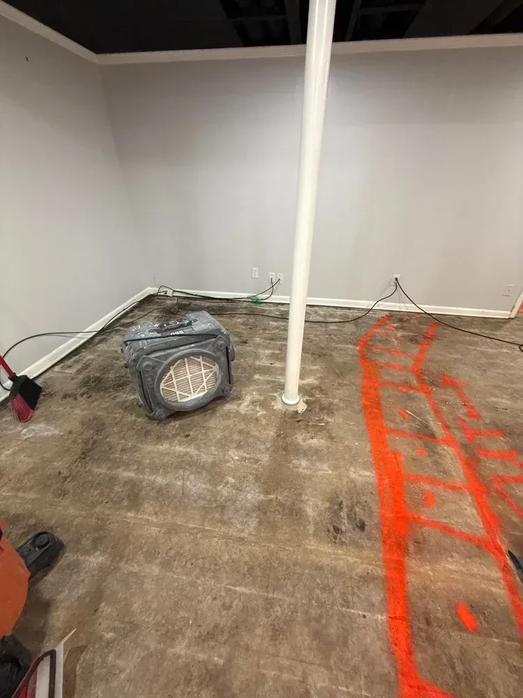 Basement room with orange concrete layout lines and a HEPA air scrubber on the floor