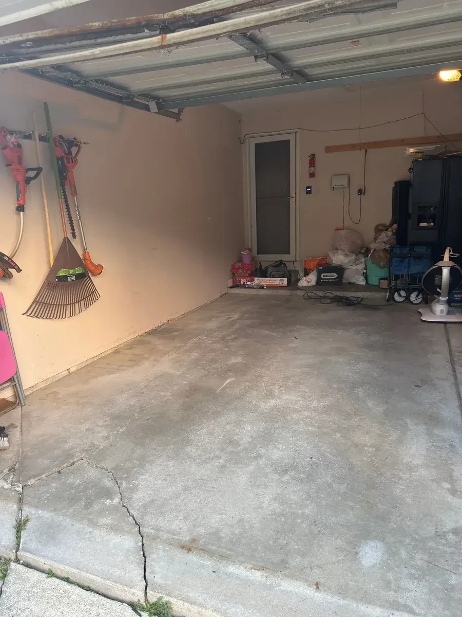 Clinton Township garage cleared after haul-away, with an open concrete floor and tools along the walls