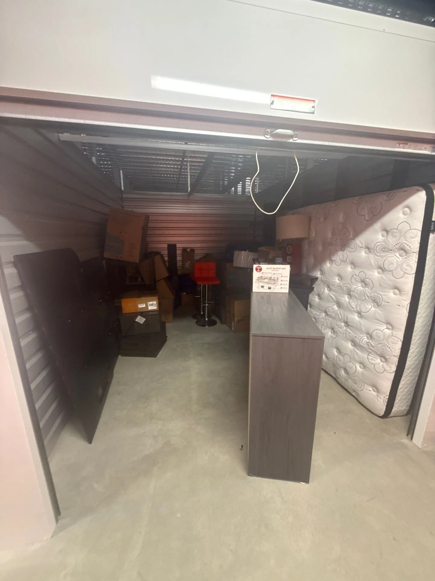 Wide view of the second-story storage unit with furniture, a mattress, boxes and household belongings before removal