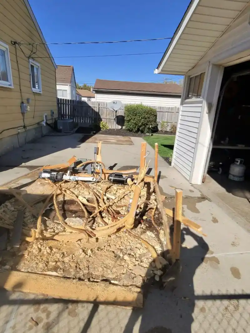Broken-down hot tub shell and components staged near the garage