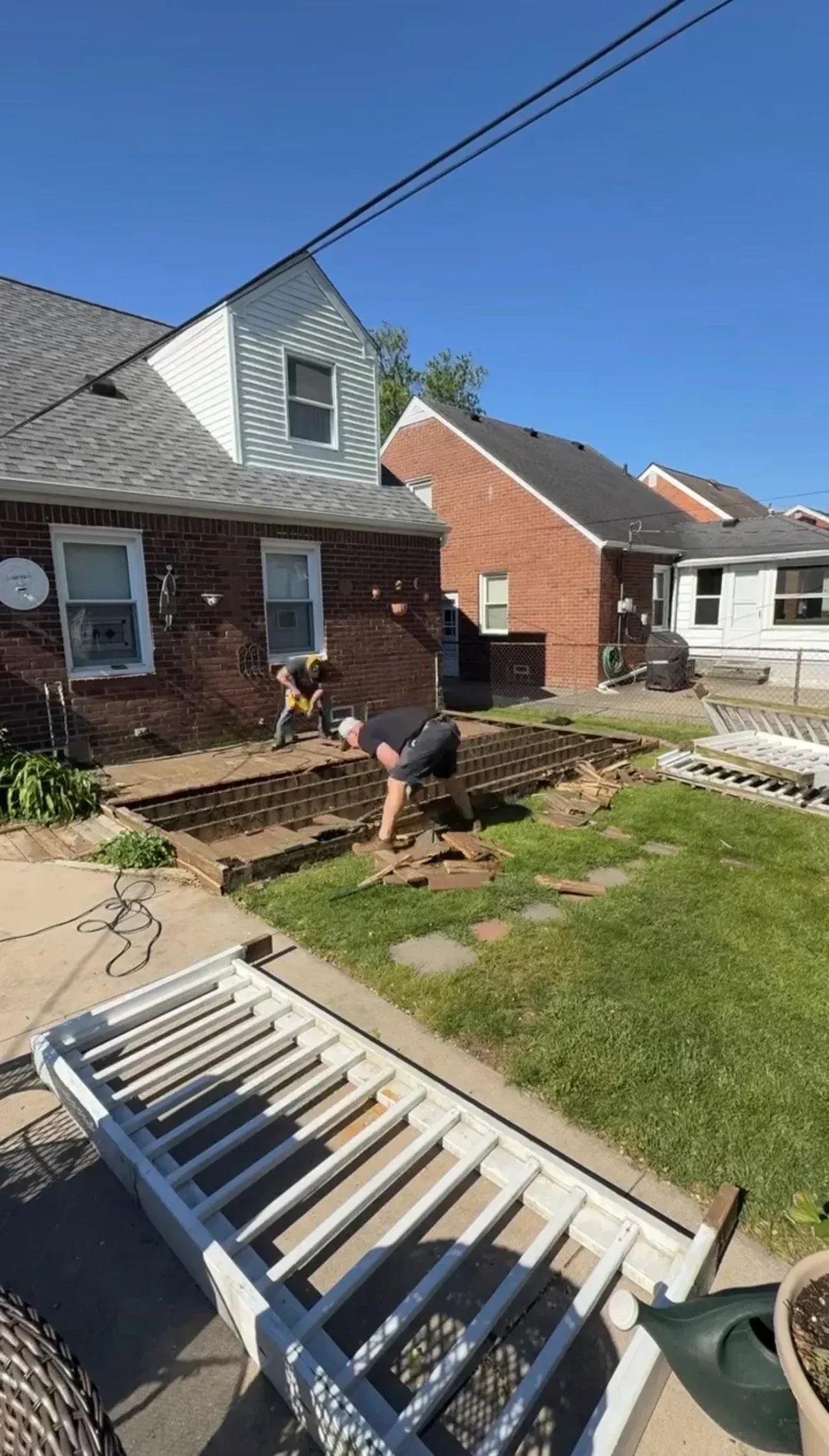 Demohaulic removing wood deck boards while the deck framing remains in Grosse Pointe Woods, Michigan