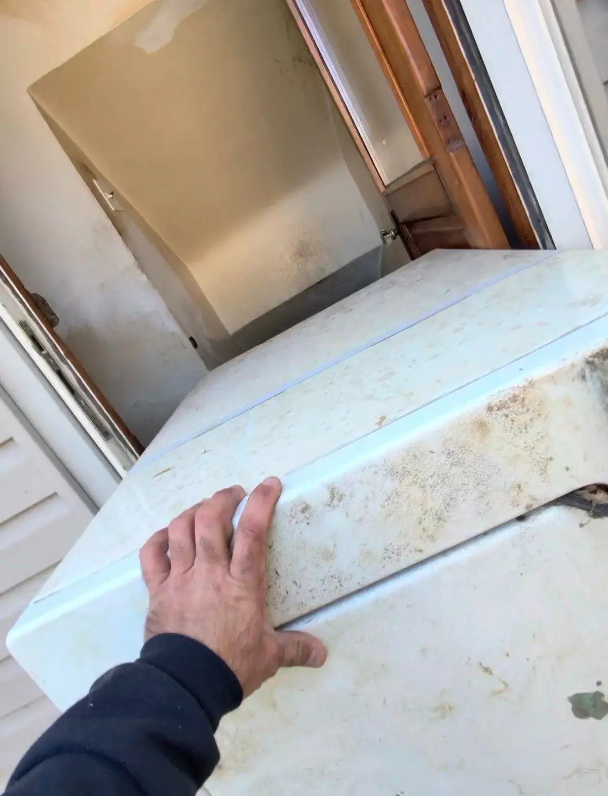 Washing machine being moved through a doorway during carry-out from a St. Clair Shores home