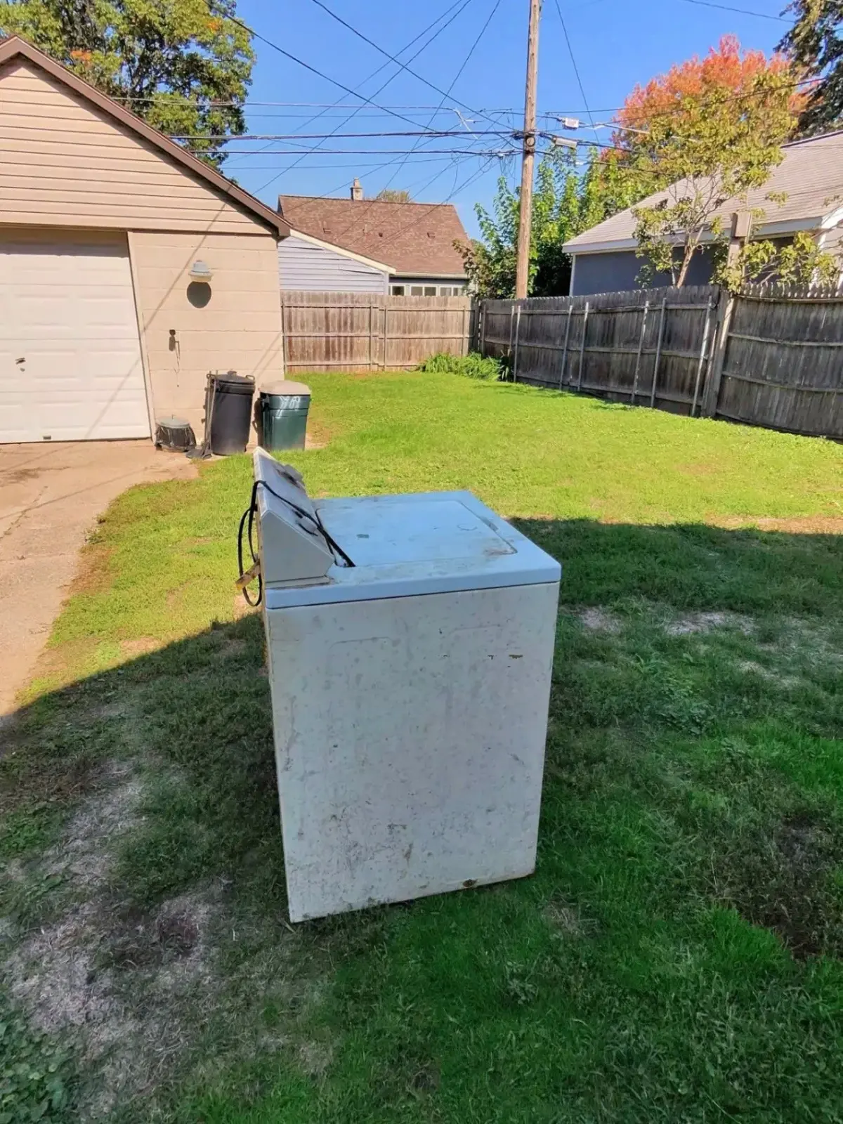 Washing machine outside on the lawn beside the detached garage after being hauled out of a St. Clair Shores home