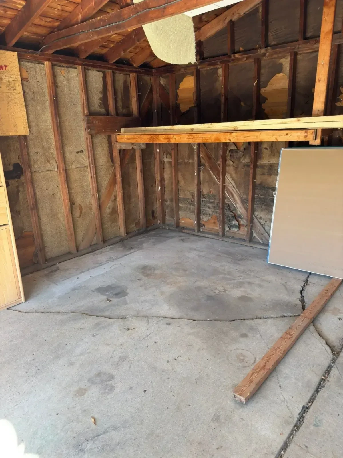 Swept St. Clair Shores garage after cleanout, with a large panel and 2x4s remaining on the floor