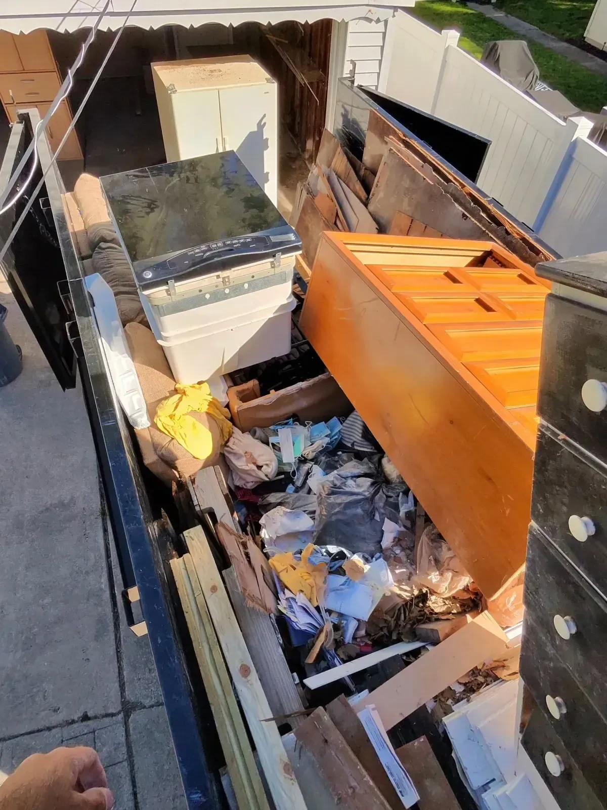 Trailer loaded with removed garage items including dressers, wood doors, furniture and other debris