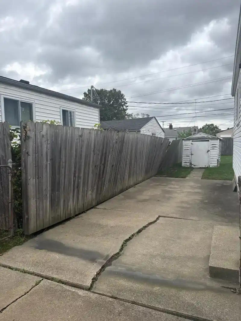 Long run of wooden privacy fence enclosing the backyard before removal