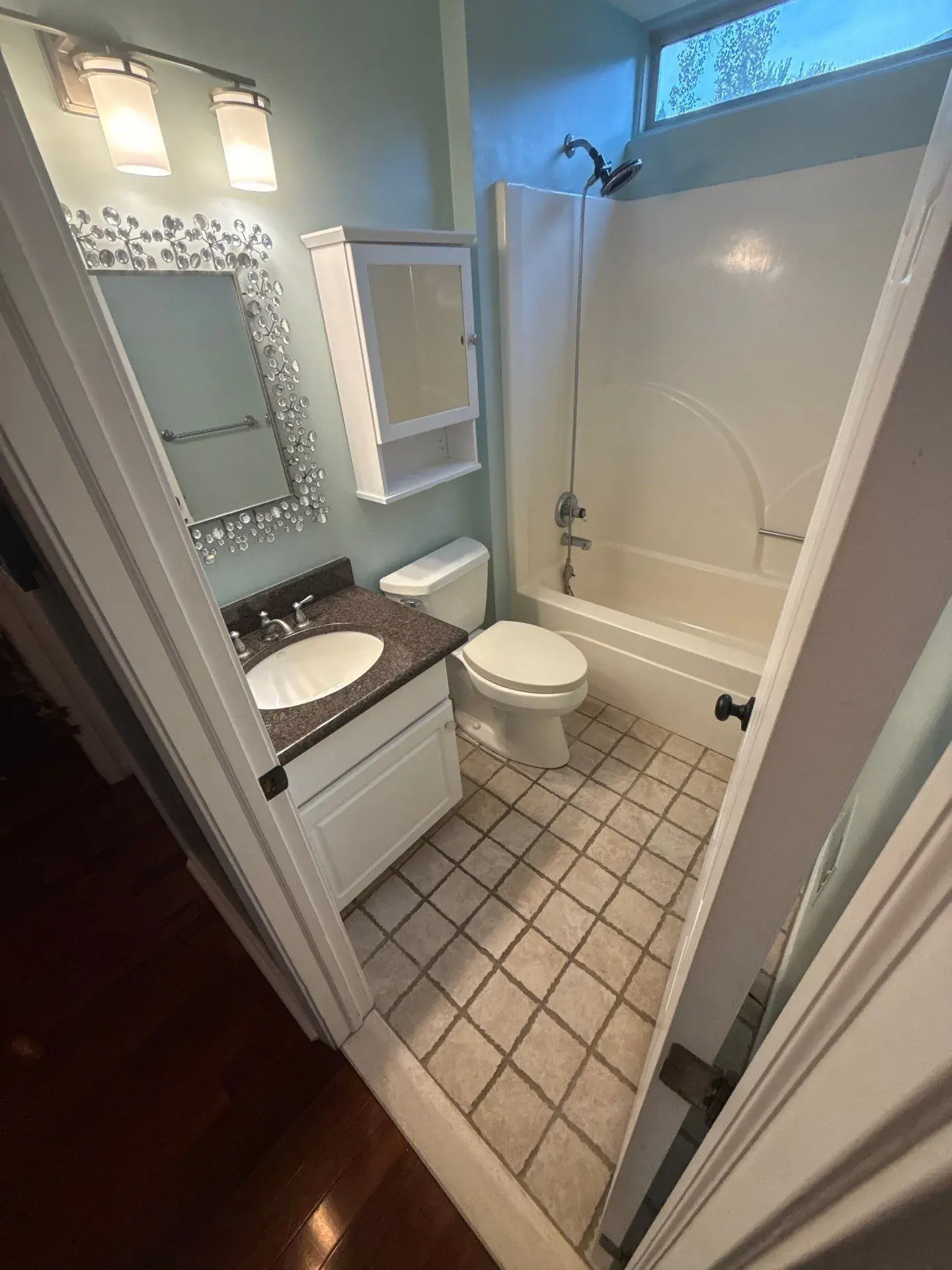 Intact Waterford bathroom with tub, surround, toilet, vanity and tiled floor before demolition