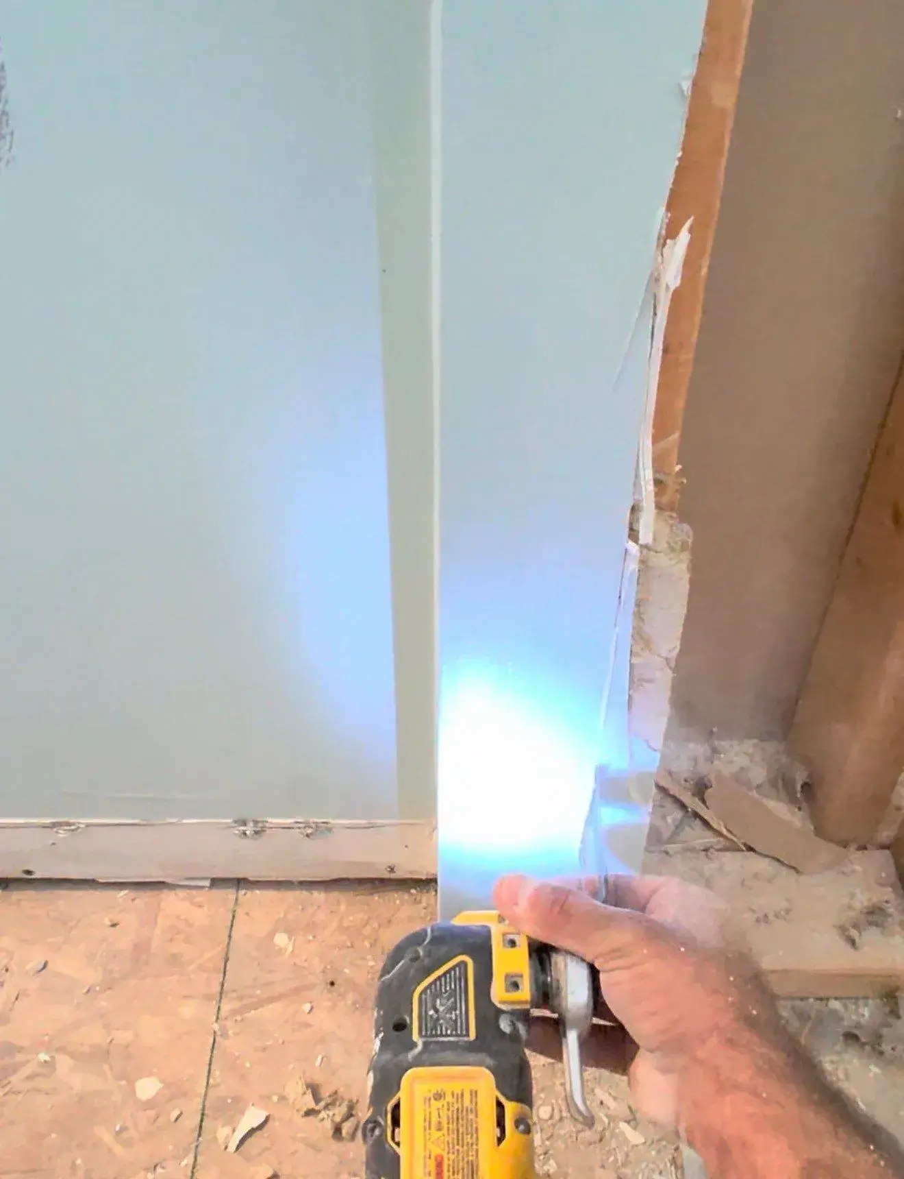 Oscillating tool cutting near an opened wall edge and exposed bathroom floor