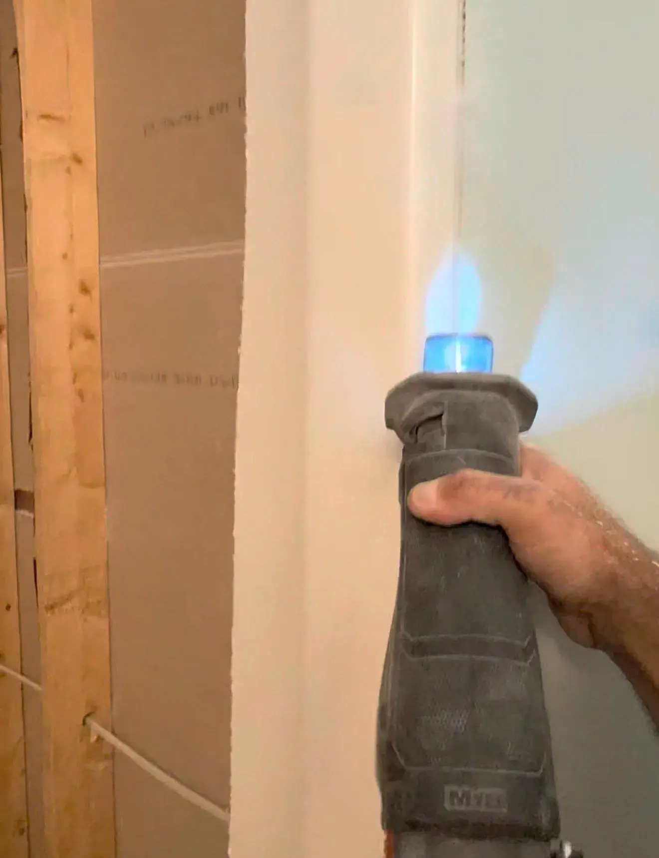 Reciprocating saw cutting the tub surround beside exposed wall framing